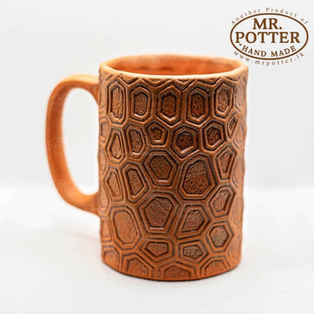 Handmade terracotta mug with geometric hexagon pattern for tea or coffee.