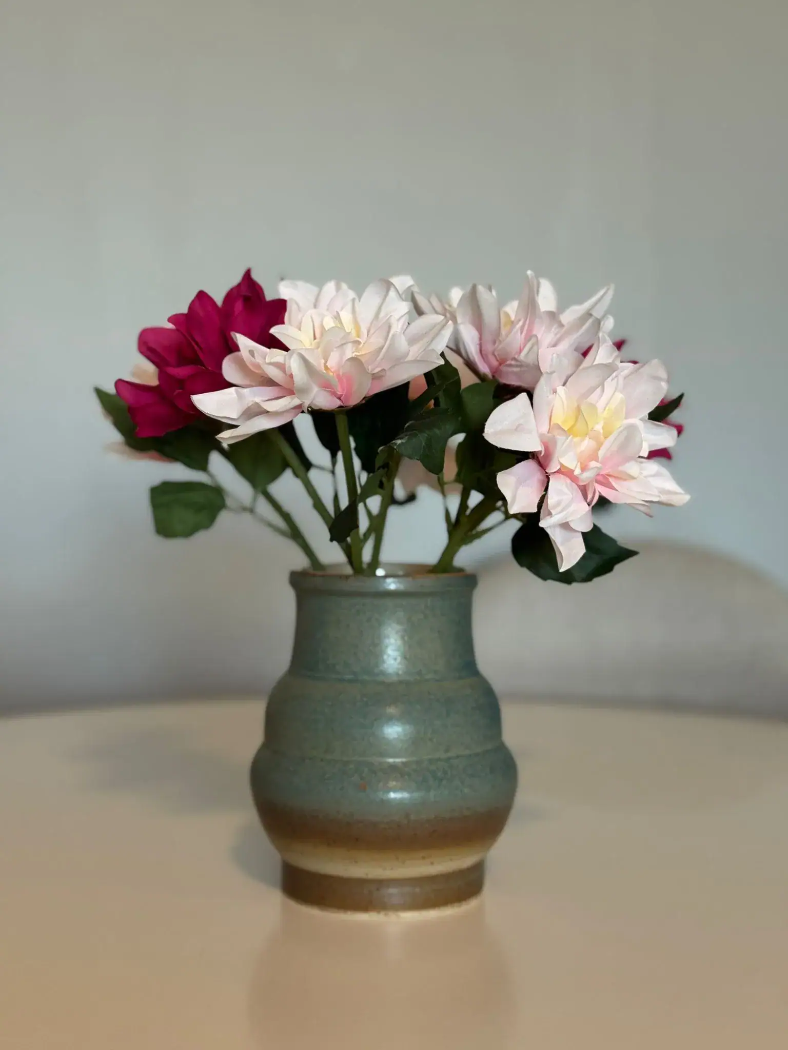 Earthy green glazed vase with pink dahlias